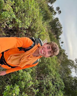 Hayden Graham smiling while hiking in an orange long sleeve shirt
